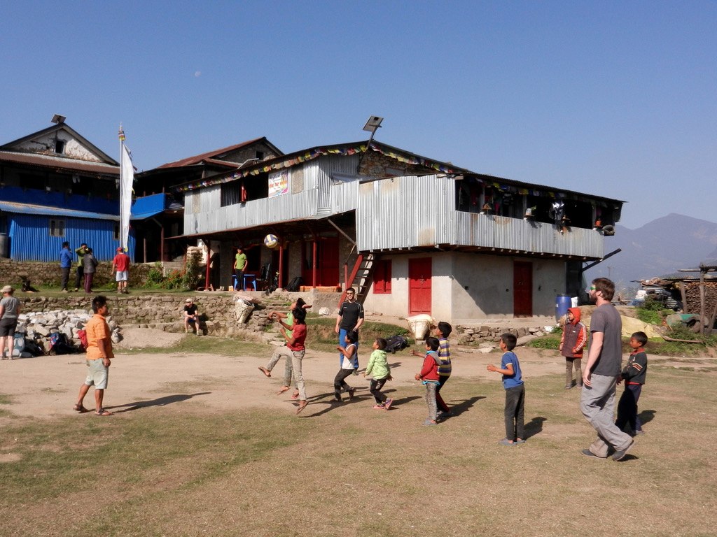 Kinder und Reisende spielen gemeinsam vor einem Gebäude in Nepal